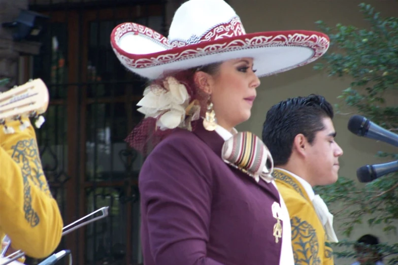 a woman standing next to another man wearing a hat