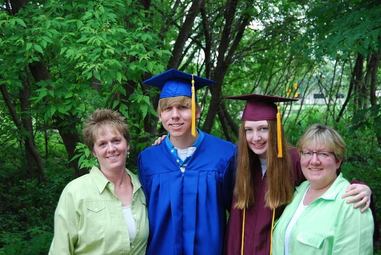 three people are posing for a picture while one woman has a graduate cap and gown on