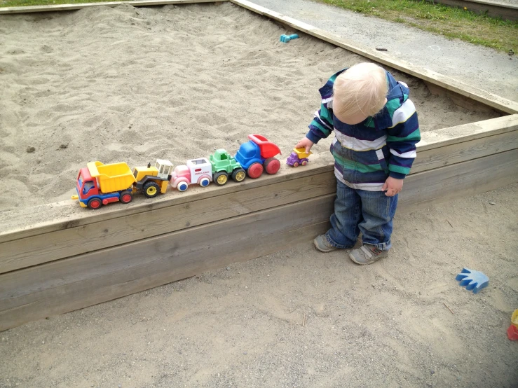 a small child stands in front of his toy train set