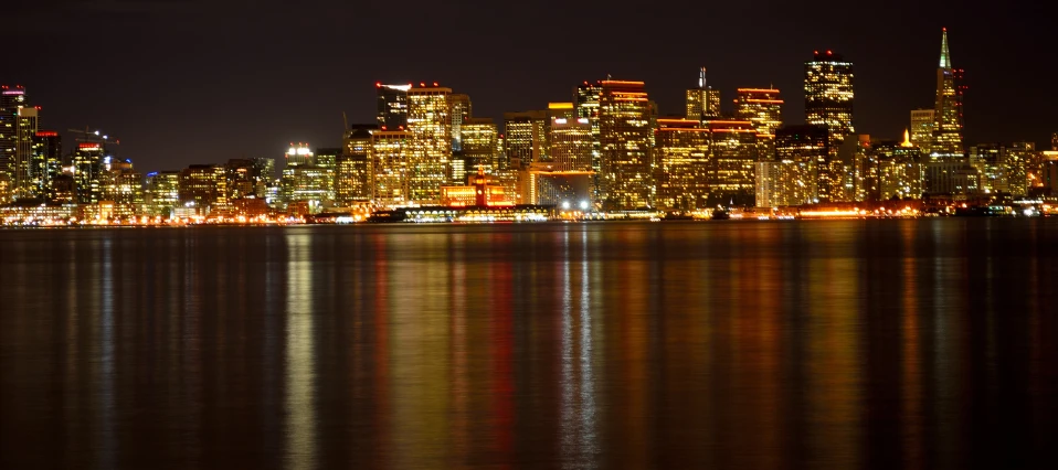 a city skyline at night with lights reflecting off the water