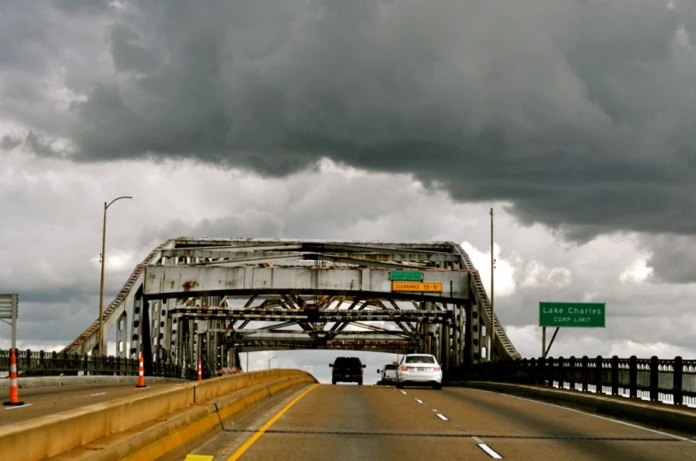 two cars driving across a large metal bridge