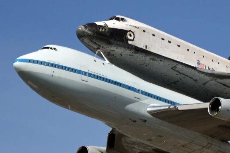 the space shuttle is riding on top of the plane