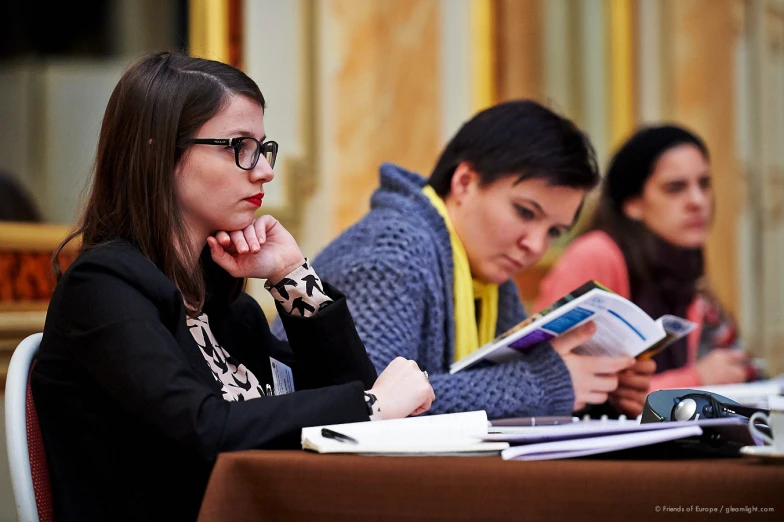 a number of people sitting at a table with a book