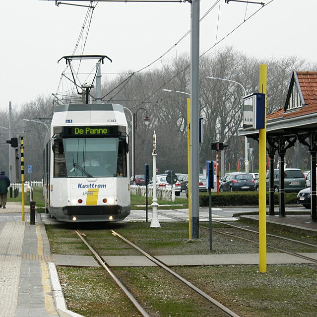 a bus traveling on train tracks with a man standing near by