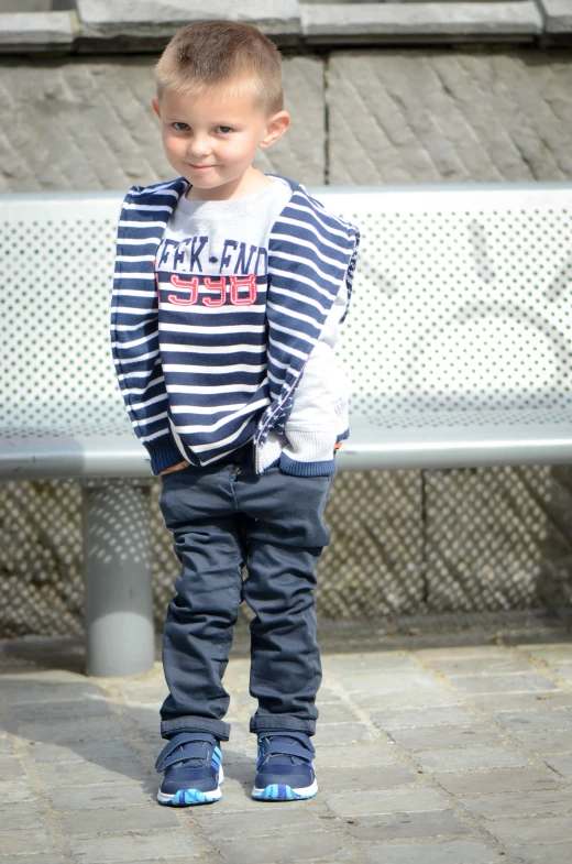 a little boy standing in front of a bench