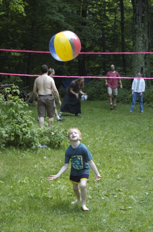a child is playing with a volley ball in the yard