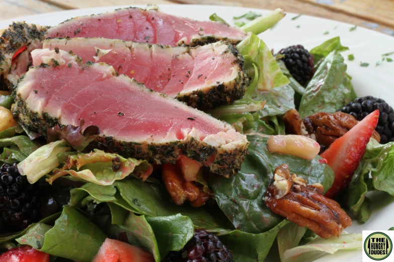 a meat and berries salad on a white plate