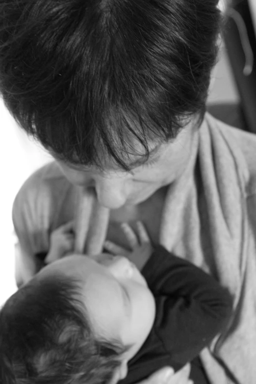 an adult holds a baby as she lays on the floor