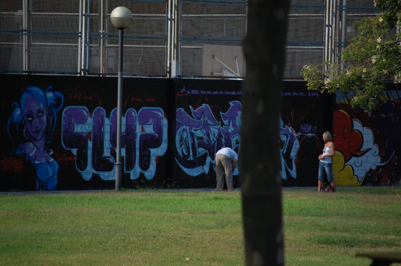 a person in a white shirt spray painting on a fence