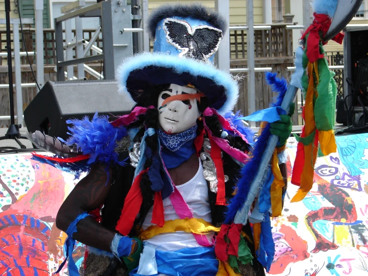 the colorfully dressed male has an umbrella attached to his neck