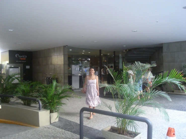 woman walking down a hall way past plants