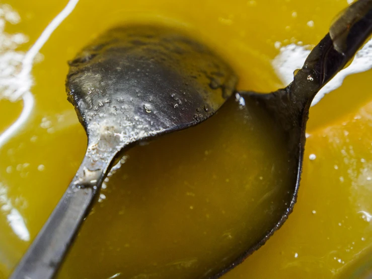 an old spoon laying in a bowl of liquid