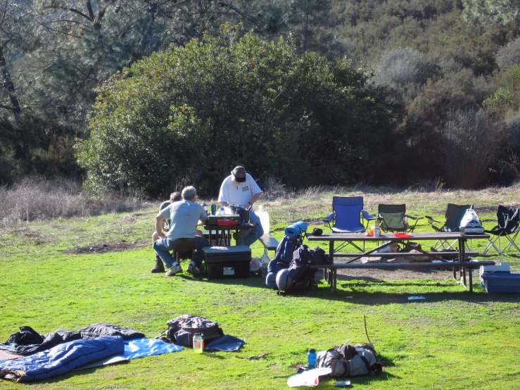 a group of people around a table with camping gear on it