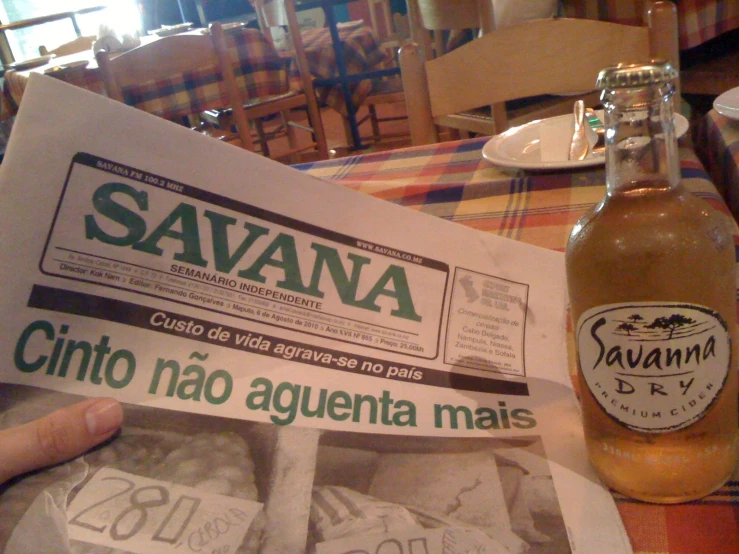an open bottle sitting next to a newspaper with a label