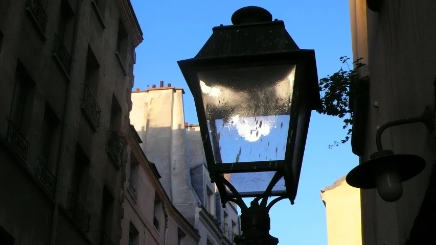 a lamp on the side of a building with blue sky