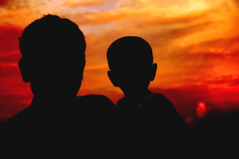 two people are silhouetted against the sun with the same background as it looks