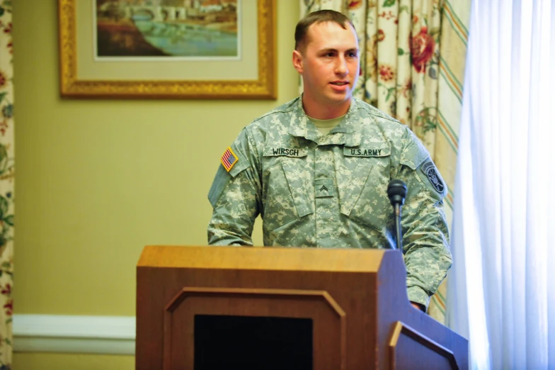 soldier speaking in front of two people in the room