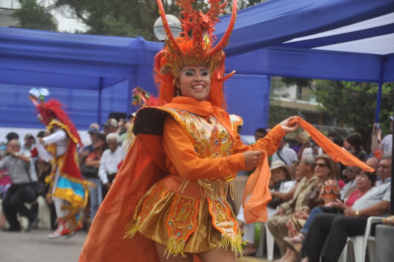 woman in orange outfit with elaborate headdress walking down the street