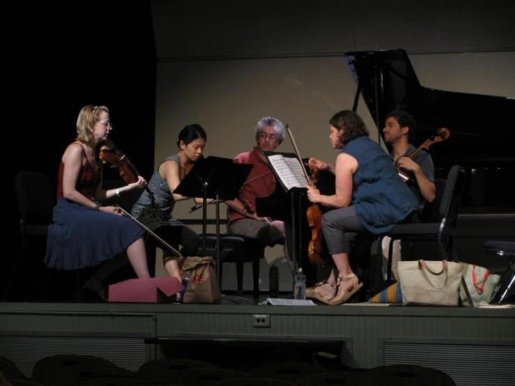 a group of people sitting on stage playing instruments