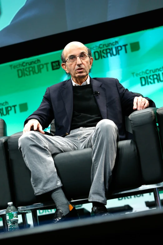 the man in a black shirt and gray pants is sitting in a chair