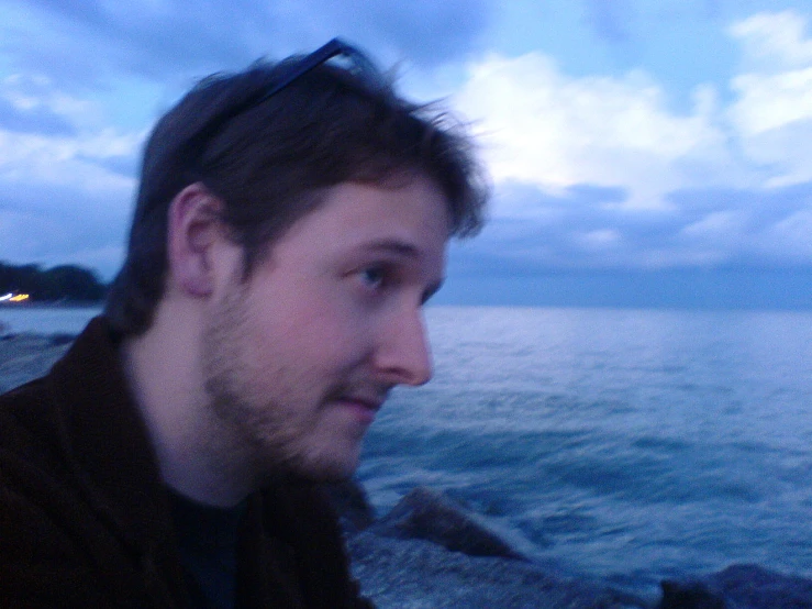 a man wearing sunglasses standing on a rocky beach