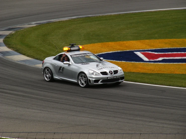 there is a silver car driving around a race track