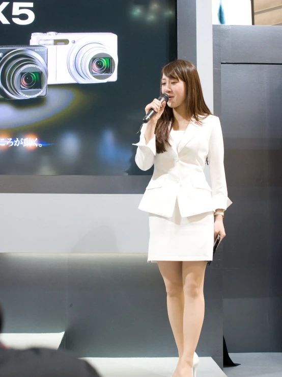 a young lady holding a microphone and wearing a white dress