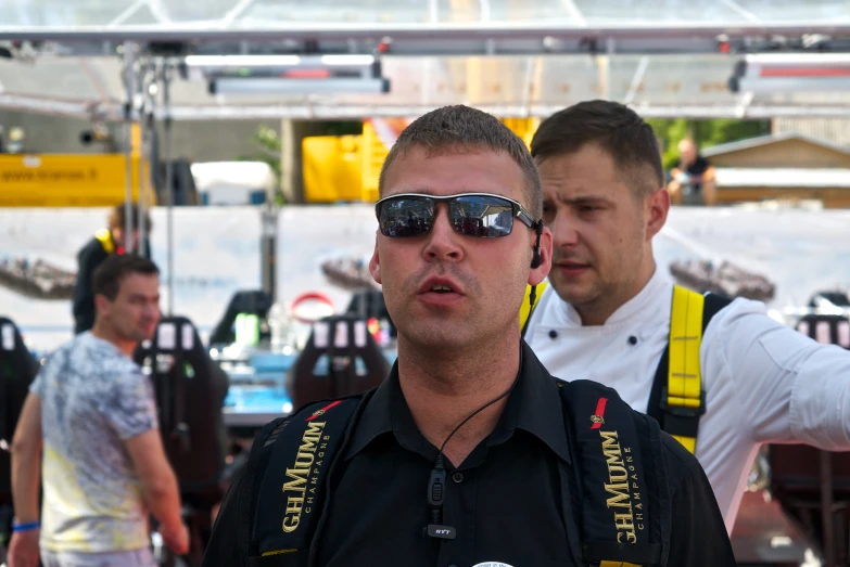 two men with sunglasses stand in the middle of a crowd