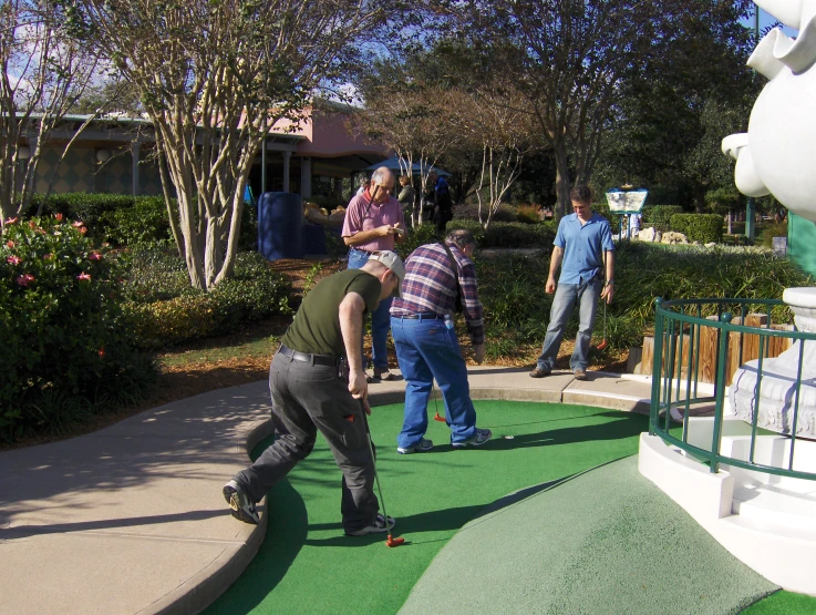 three people on miniature golf putting green in front of the house