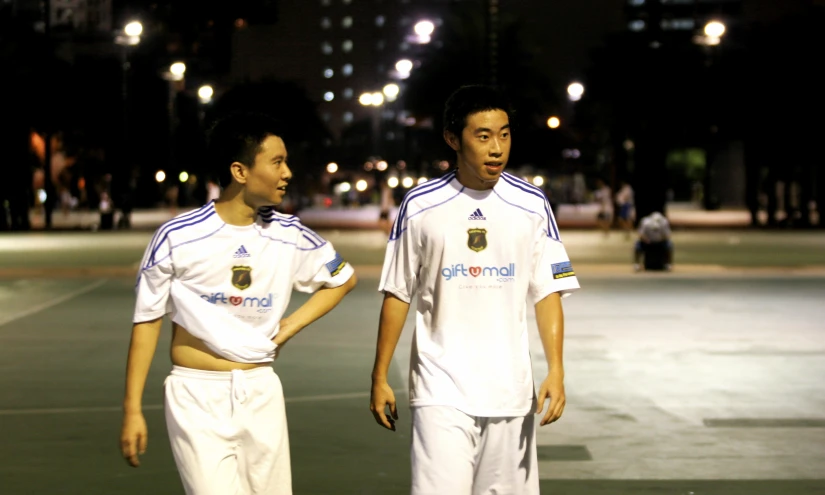 two asian guys in soccer jerseys at night