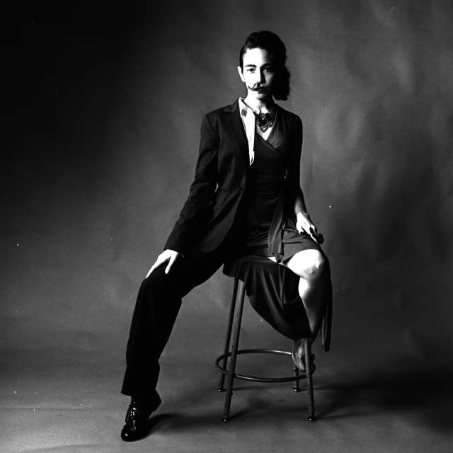 a man is posing on a chair while wearing a suit