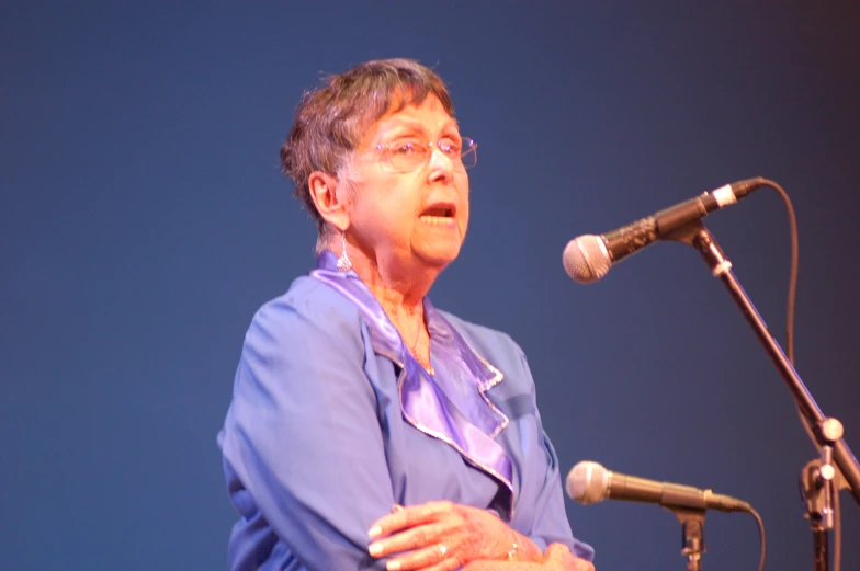 a woman is standing in front of a microphone and speaking