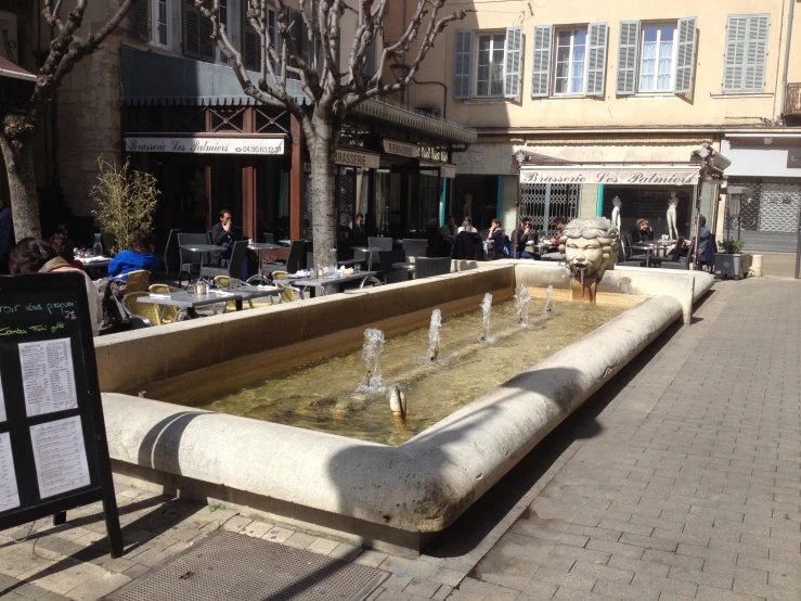 some tables and people in a fountain near buildings