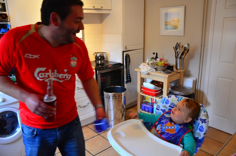 a man standing over a small child who is in a high chair