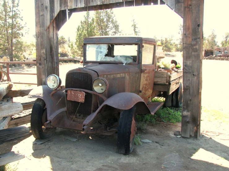 an old truck sitting in a small wooden structure