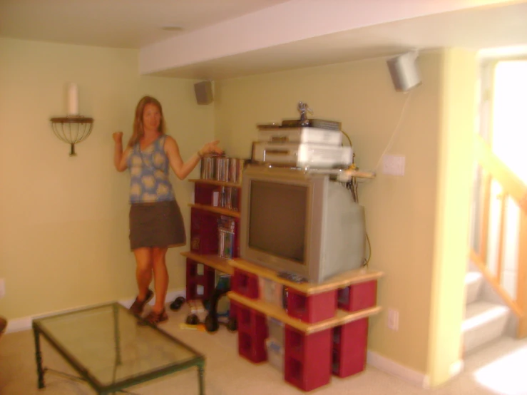 a woman standing in a room with books and a tv