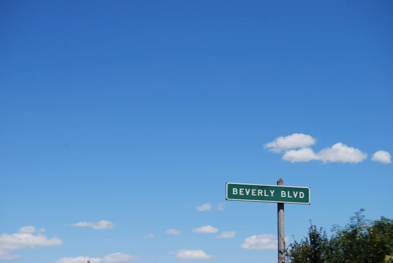 a sign in front of a blue sky that reads beverly boulevard