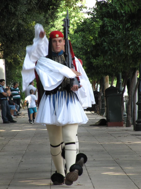 a woman in a costume walks down the street with a machine gun