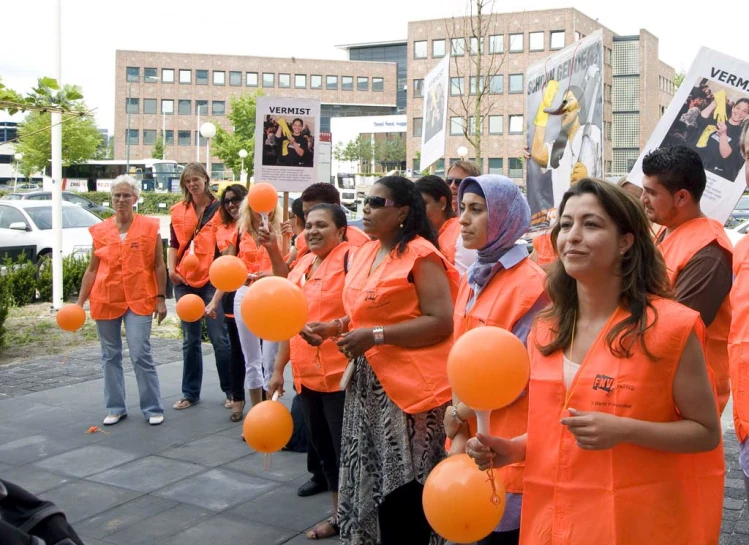 women in orange shirts holding up orange balloons