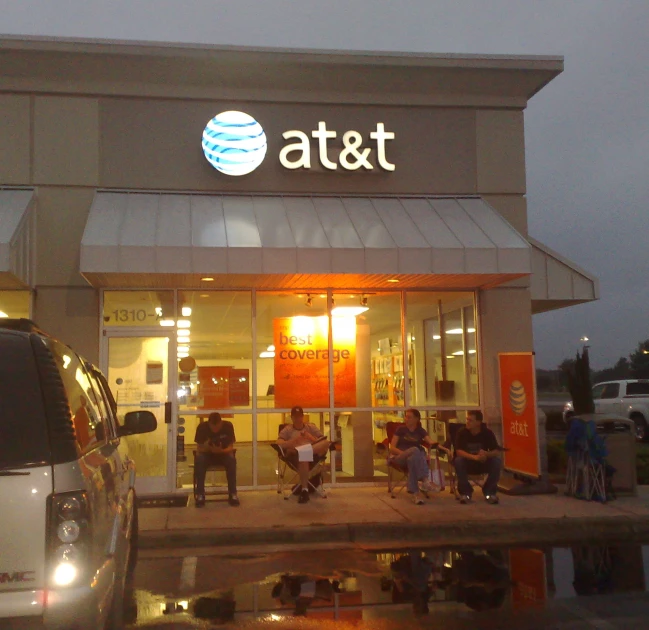 a group of people sit on a bench outside of the at & t