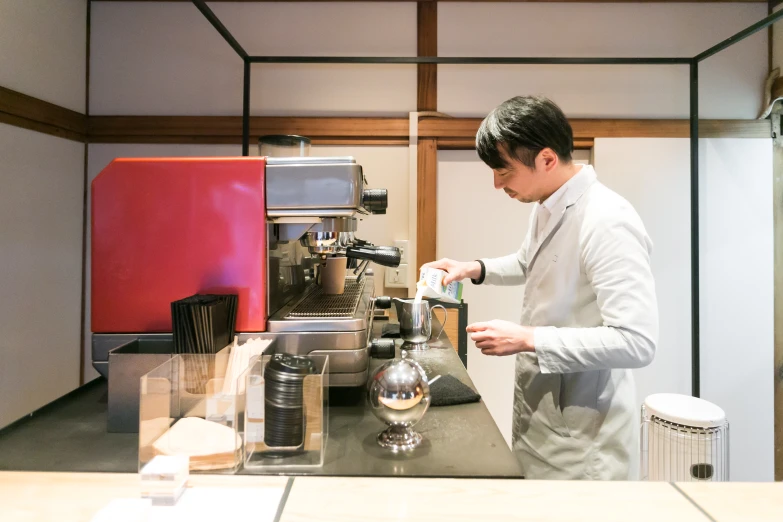 a man standing at a counter with a cup and machine