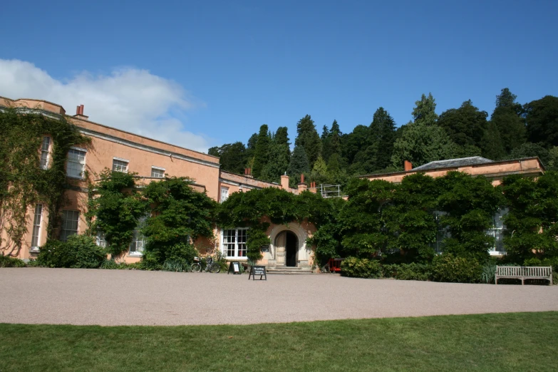 the brick building has many windows and a lot of greenery growing outside