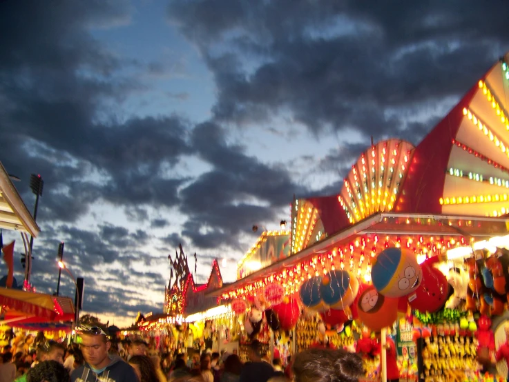 a crowd of people standing around in front of a carnival ride