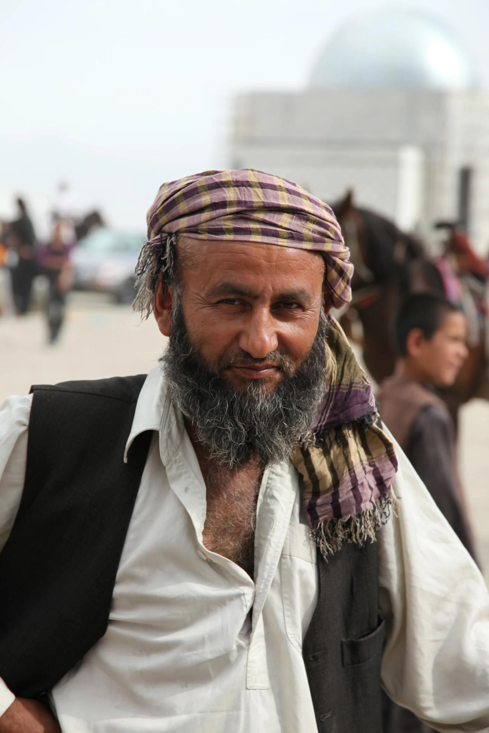 a man with a white beard is standing by some horses