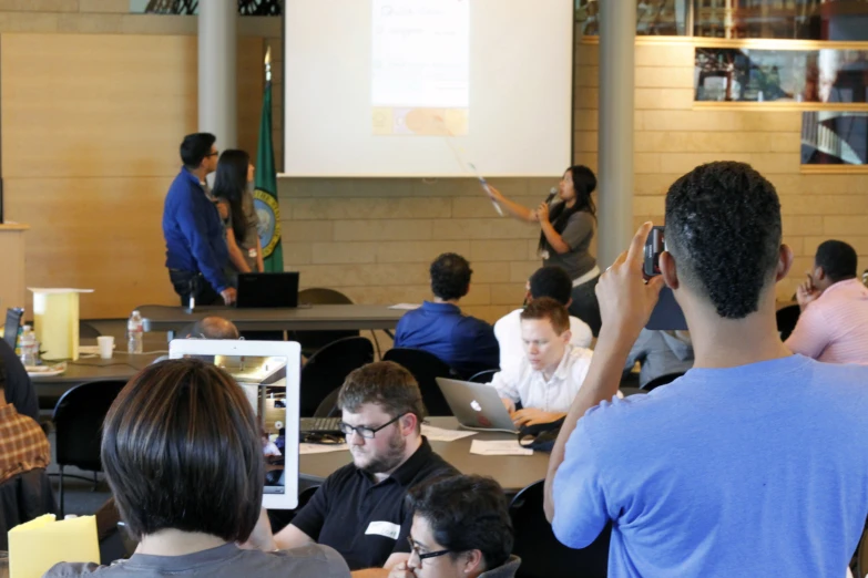 people in a room watching a person on the laptop