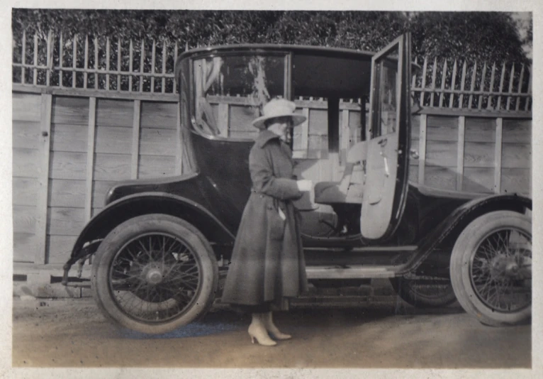 a woman standing in front of an old fashion vehicle