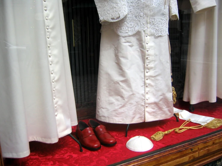 a pair of shoes, some clothing and a hair clip sitting on a stand