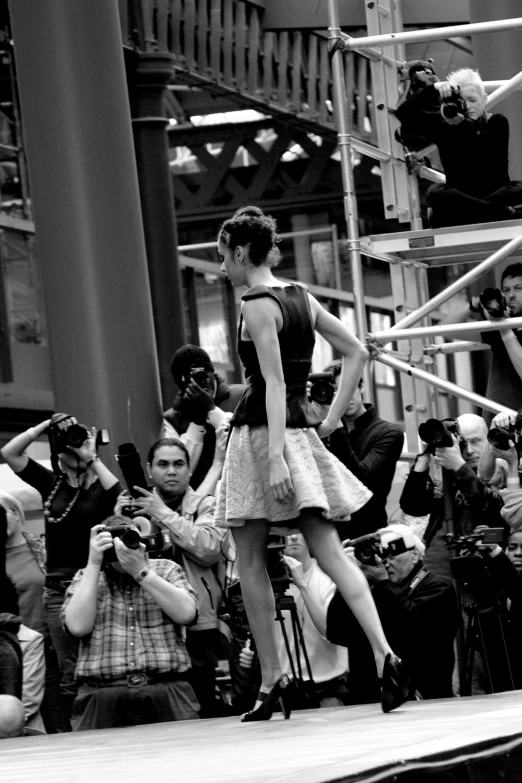 a woman is walking down the runway while taking pictures