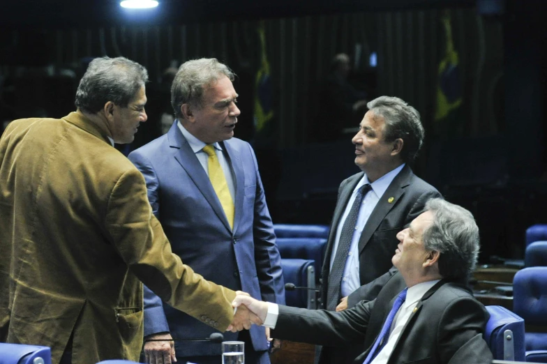 several men shake hands in front of a table