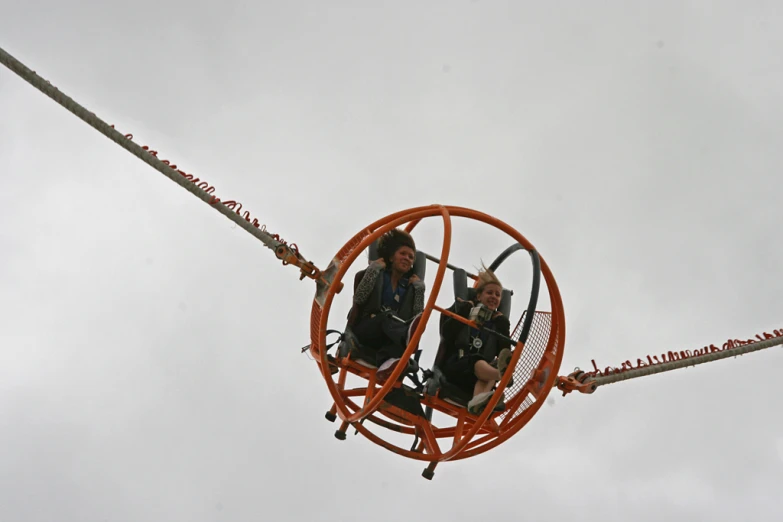 four people on an orange device in a cloudy sky